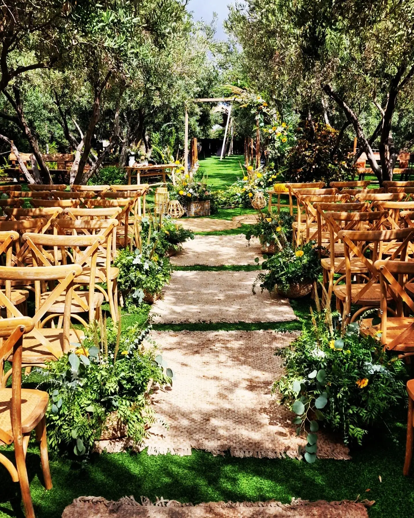 El pasillo de una ceremonia: sillas de madera a ambos lados, flores y losas