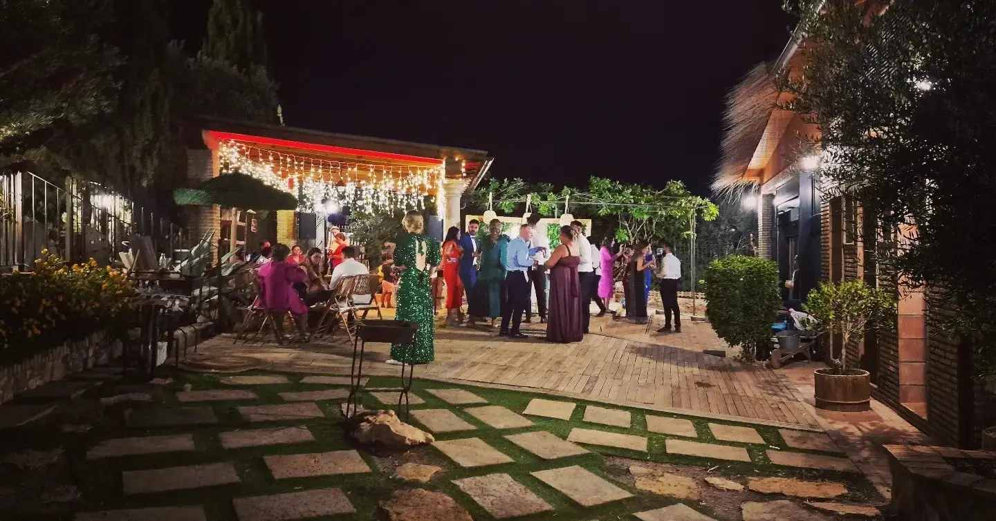 La fiesta de noche en la plaza, con losas, cortinas de luces y los invitados de pie